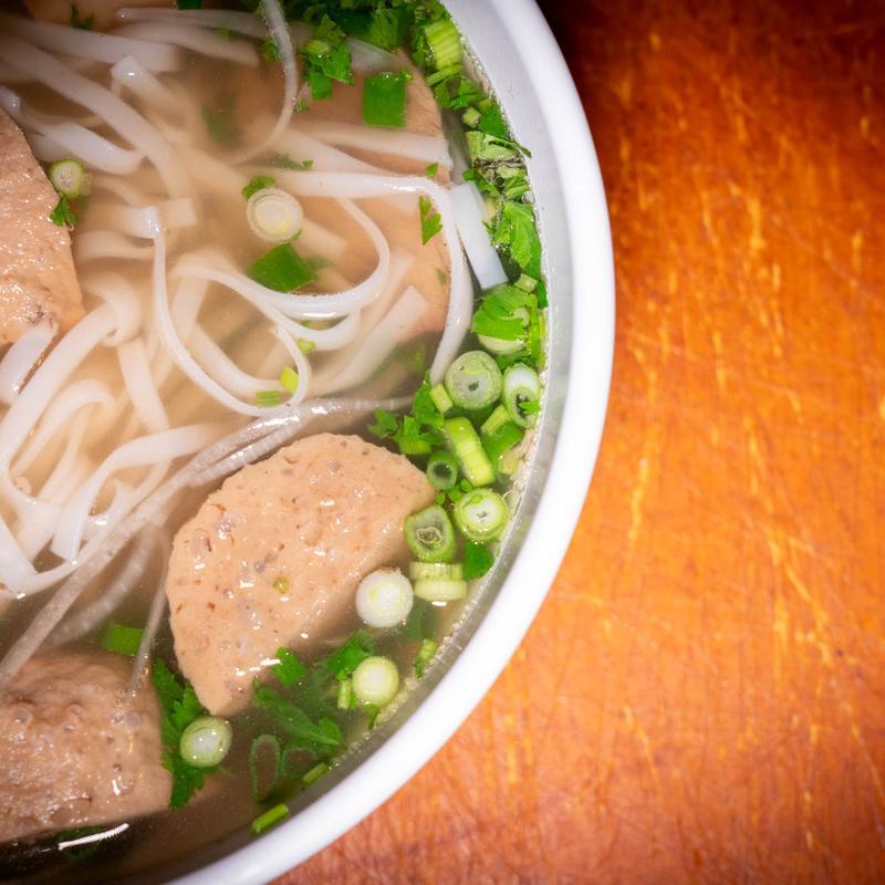 Bowl of beef pho with rice noodles, meatballs, scallions, cilantro
