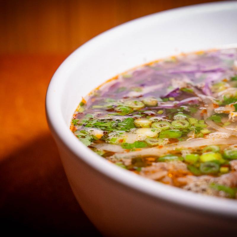 Bowl of beef pho with scallions, cilantro, and sliced onions