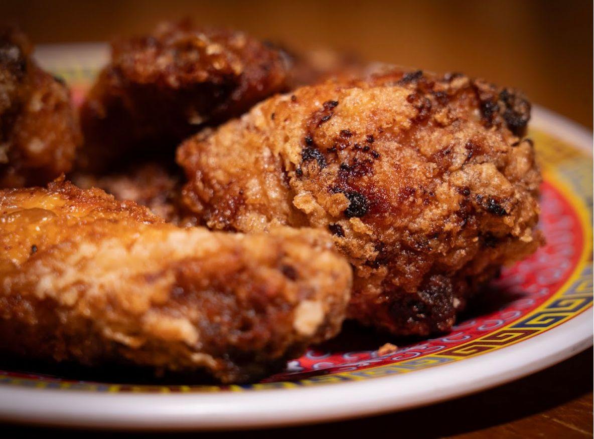 Crispy fried chicken wings with golden breading on patterned plate