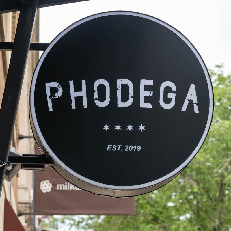 Round black restaurant sign reading "PHODEGA" with EST. 2019 and stars