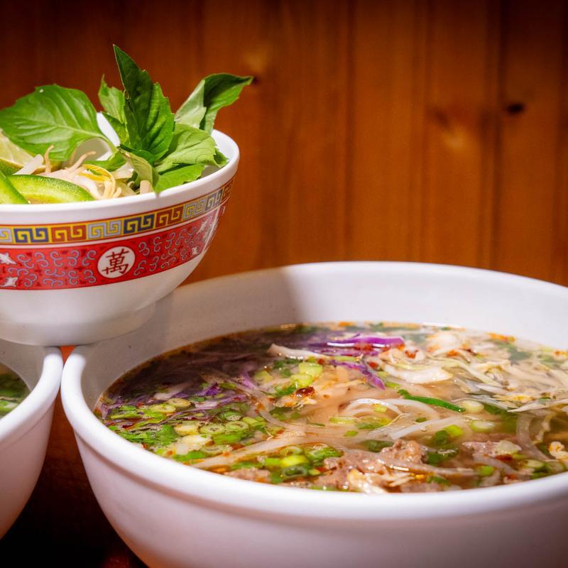 Beef pho bowl with rice noodles, scallions, basil, and lime wedges