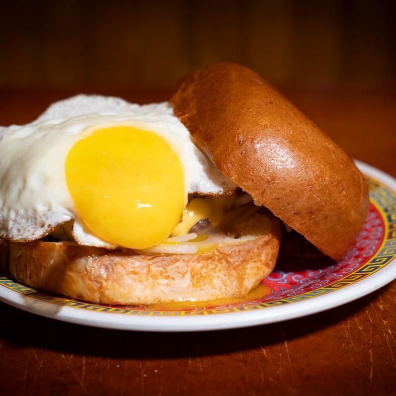 Breakfast burger with fried egg, melted cheese, and brioche bun